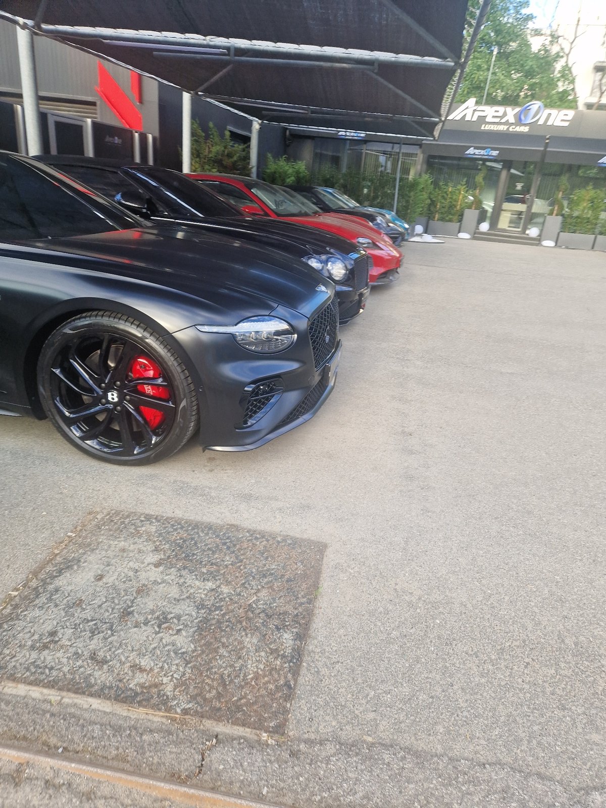 Person visits luxury car dealership, photographed outdoors