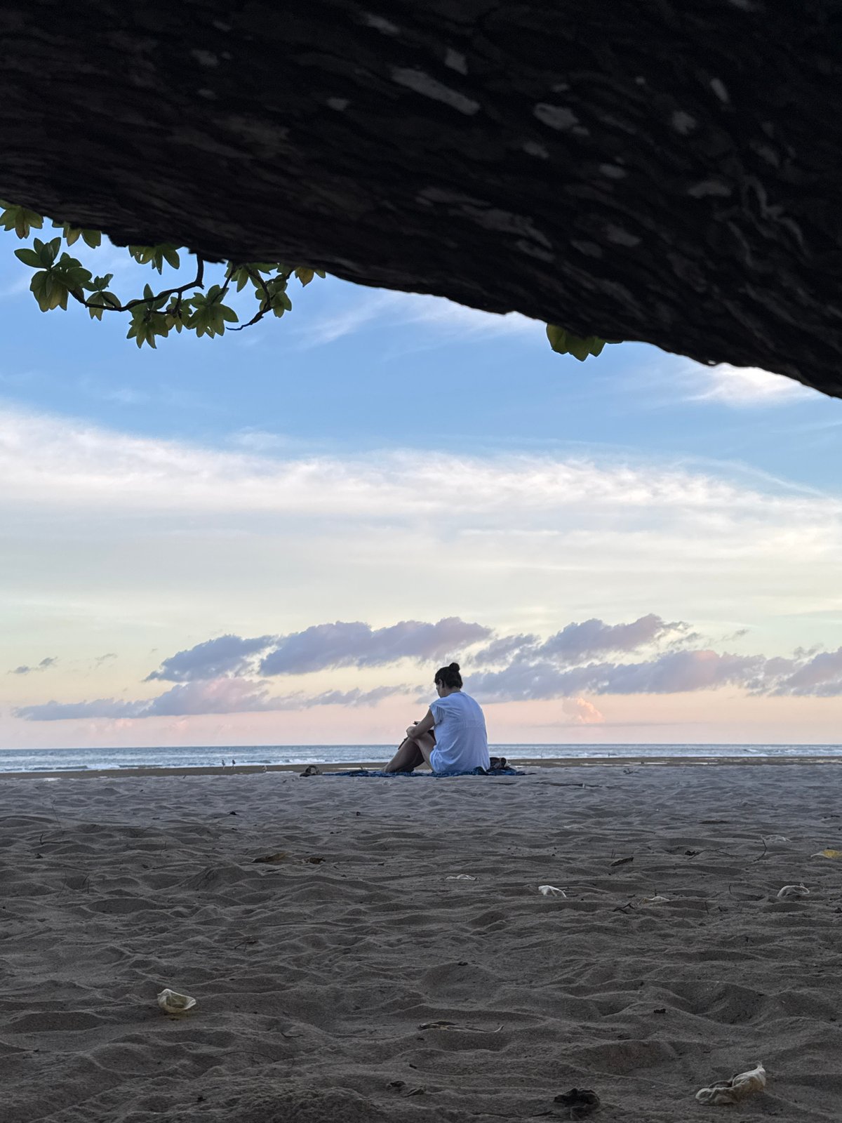 Person sits on Nusa Dua beach under cloudy skies