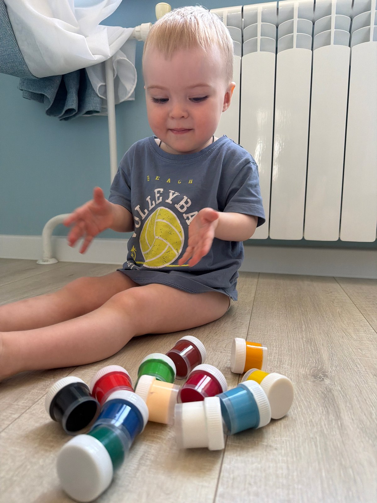 Child plays with paint containers on floor in Votkinsk