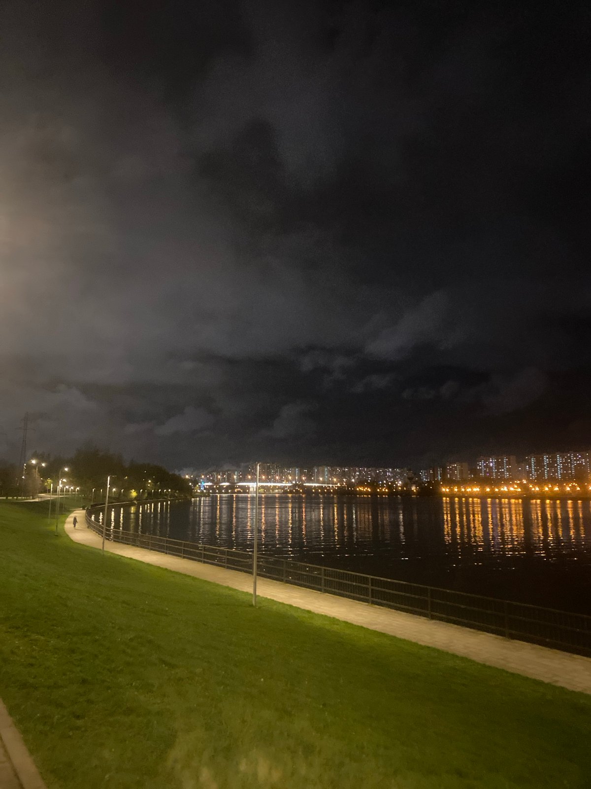 Nighttime city skyline viewed from waterfront pathway