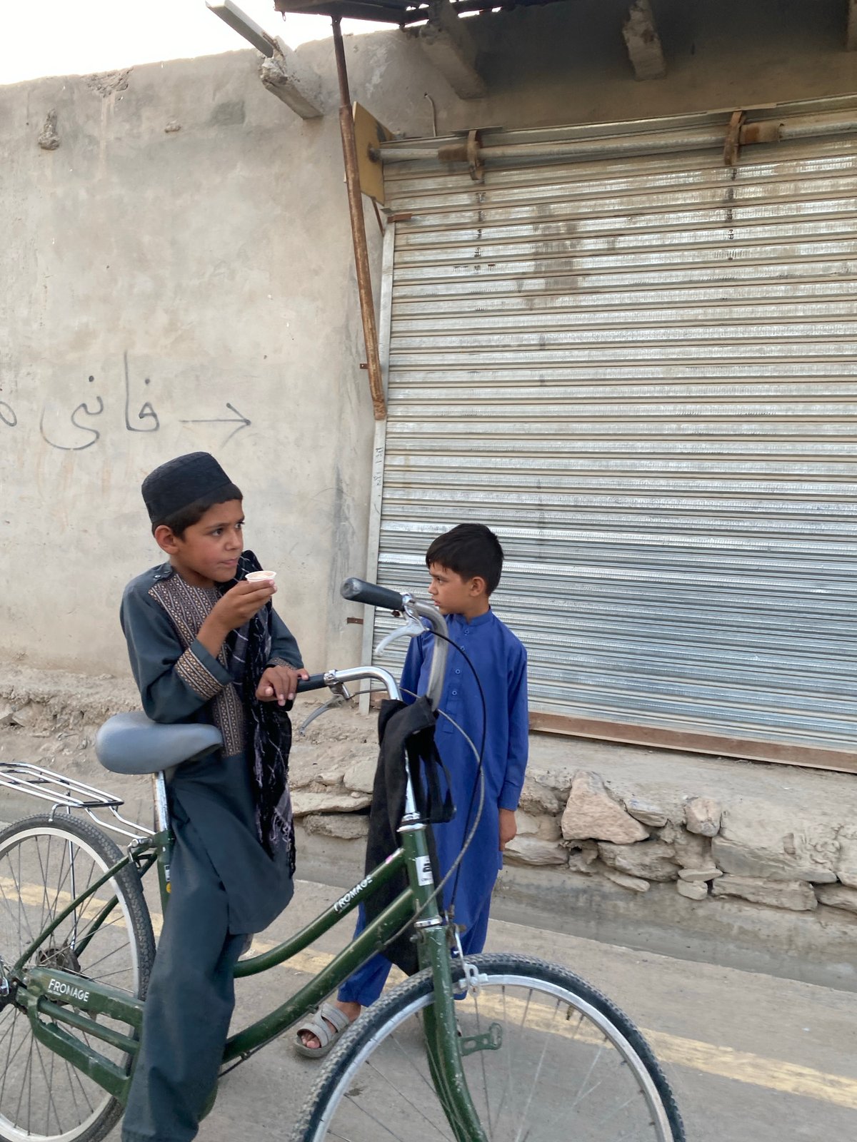 Street scene near shuttered shops in Kandahar, bicycles and traditional dress