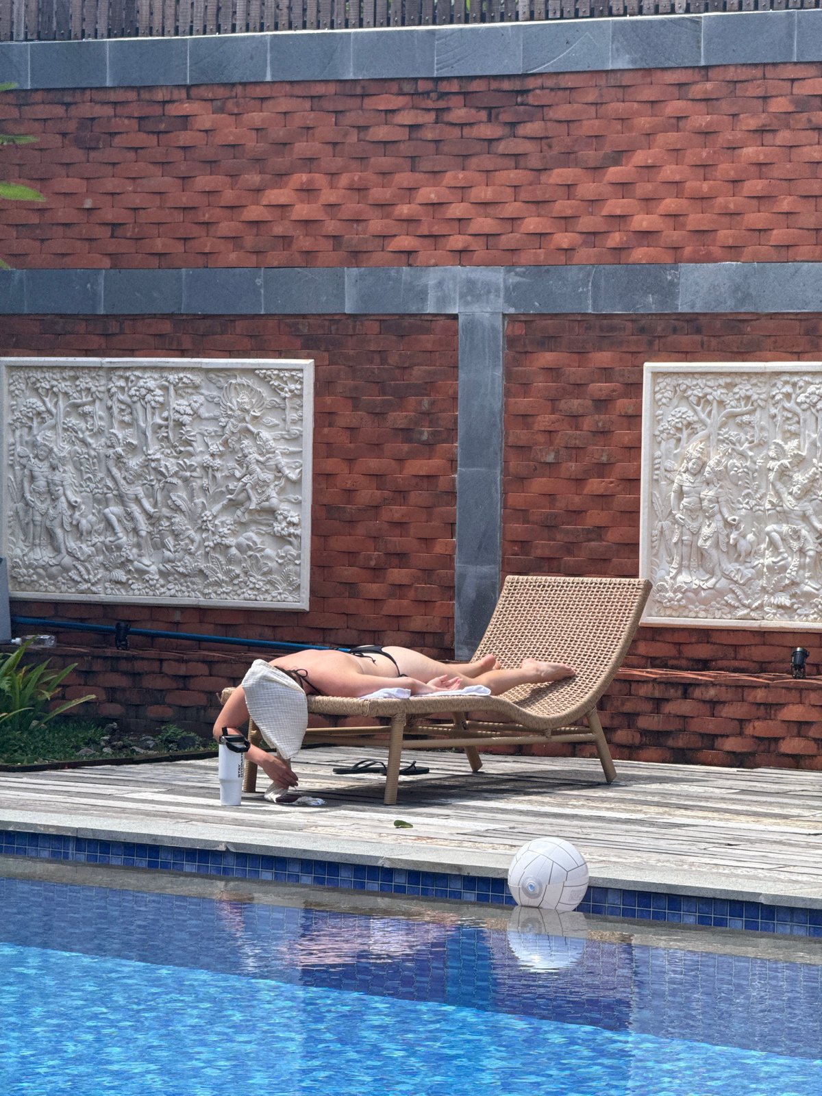 Woman sunbathes poolside in early morning North Kuta