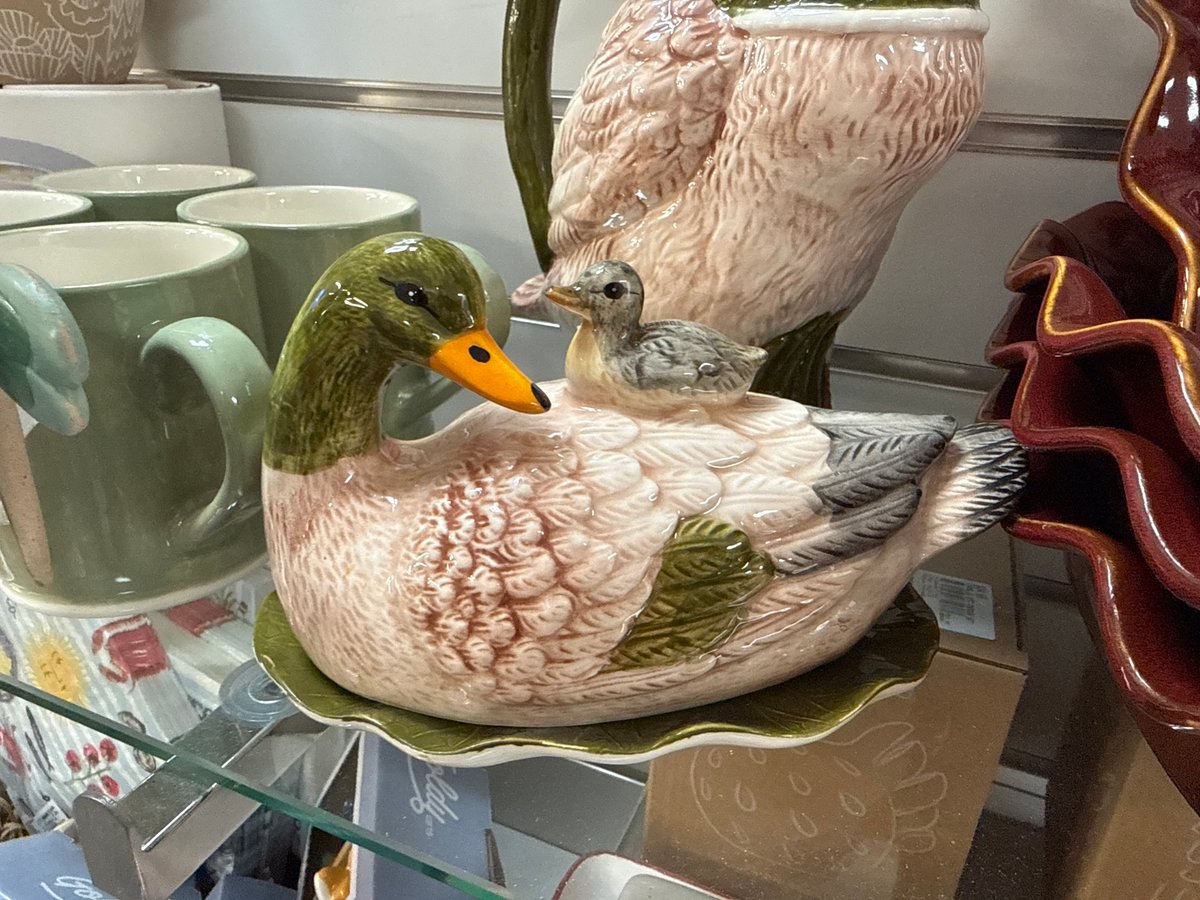 Ceramic duck and duckling figurine on a glass shelf