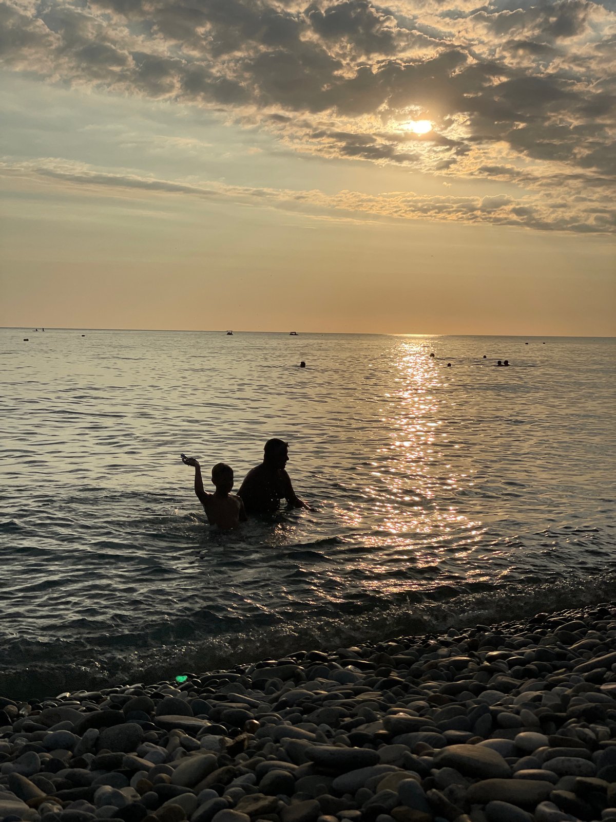 Sochi pebble beach at sunset, calm water and cloudy skies