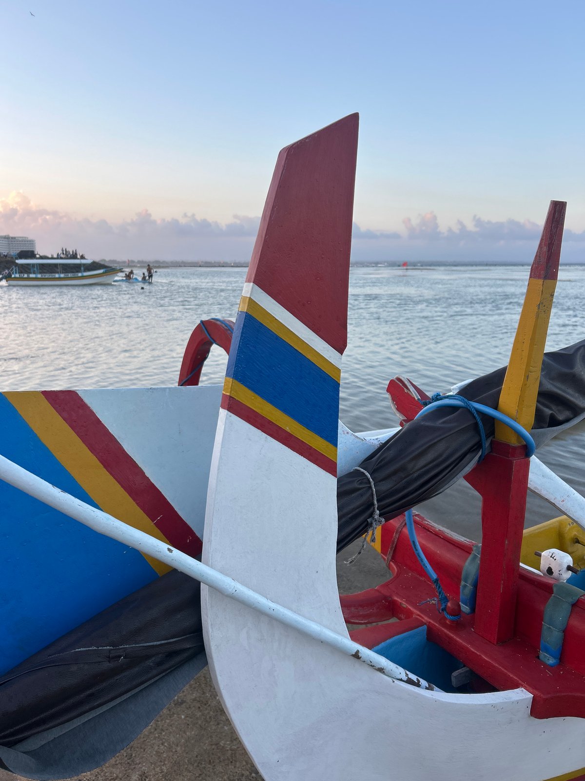 Balinese beach morning: jukungs, temple statues, and shoreline life
