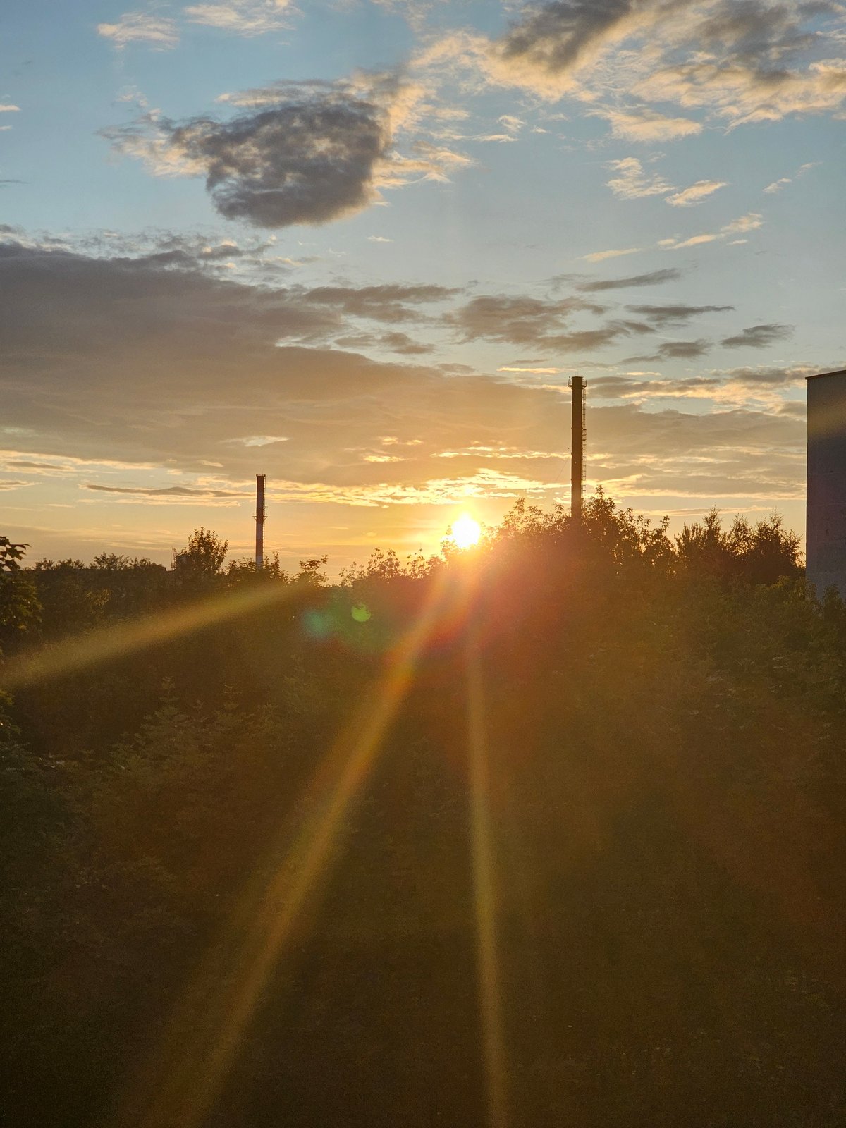 Golden sunset over Khimki, framed by chimneys and trees