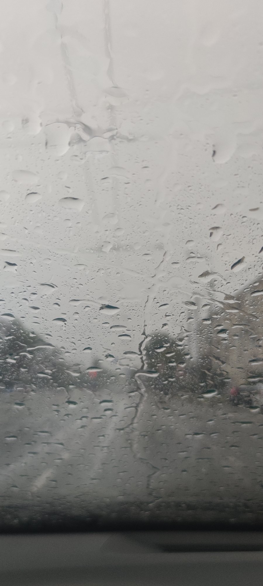 Rain-soaked city streets seen through a wet windshield