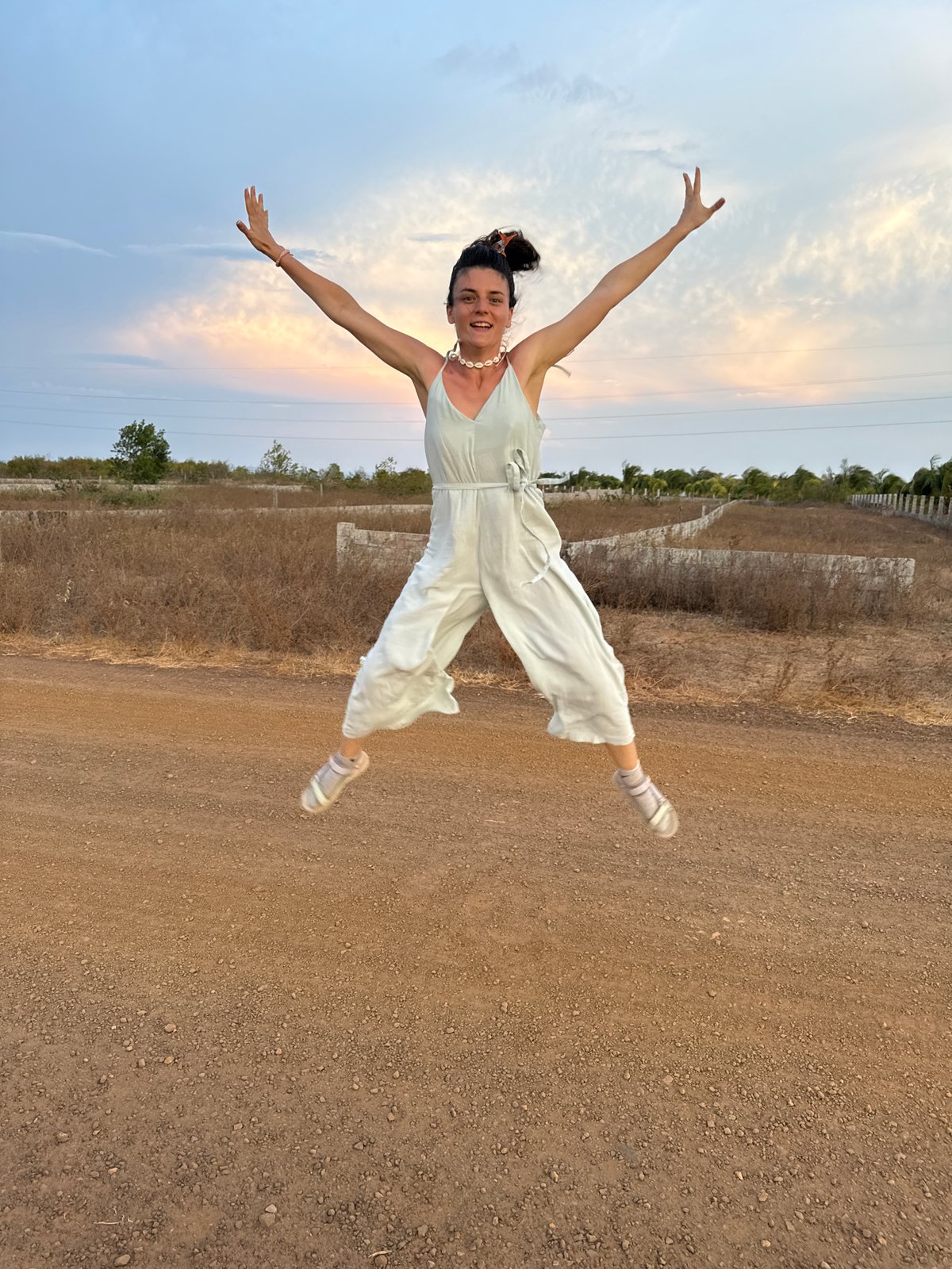 Woman jumps joyfully on dirt road in Mũi Né
