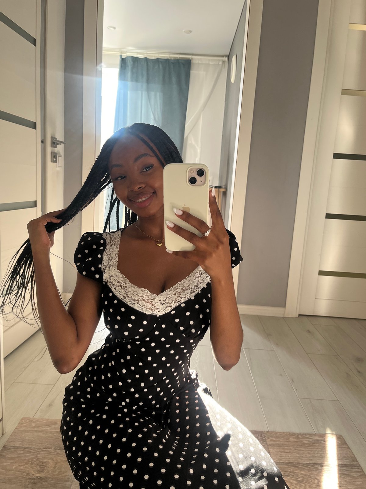 Woman takes selfies in polka dot dress indoors