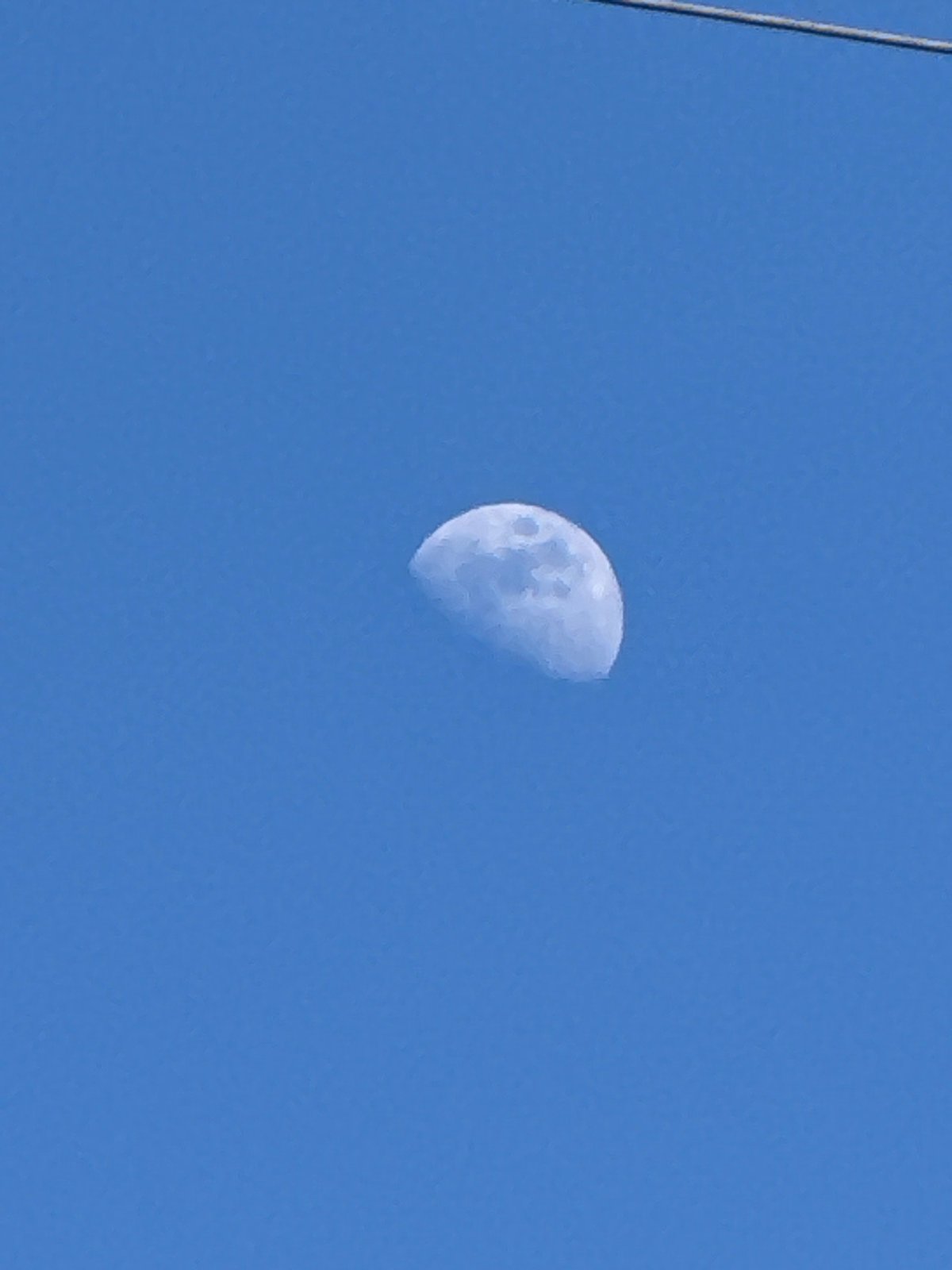 Half-moon visible in clear daylight sky over French commune