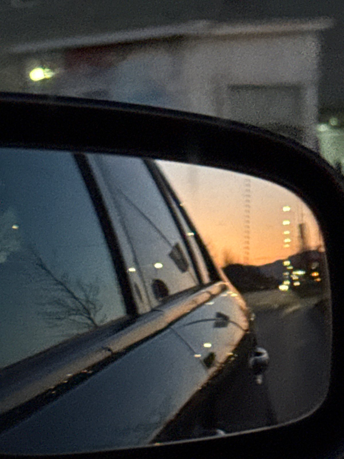 Car mirror captures nighttime street reflection in Sofia
