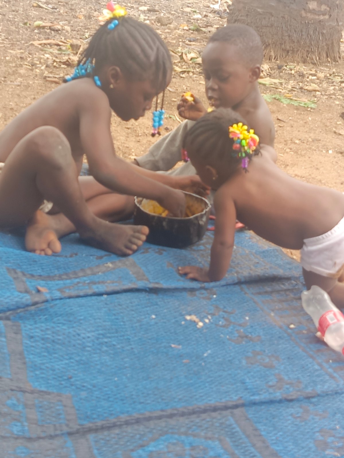 Children share outdoor meal on mat in Akwanga, Nigeria