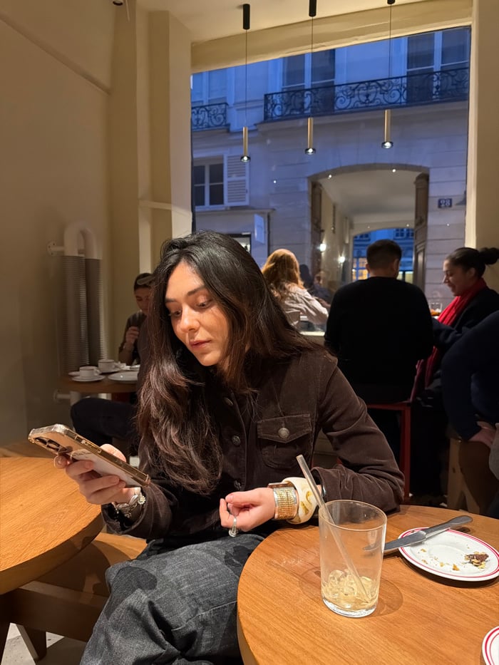 Woman uses smartphone at Paris cafe table