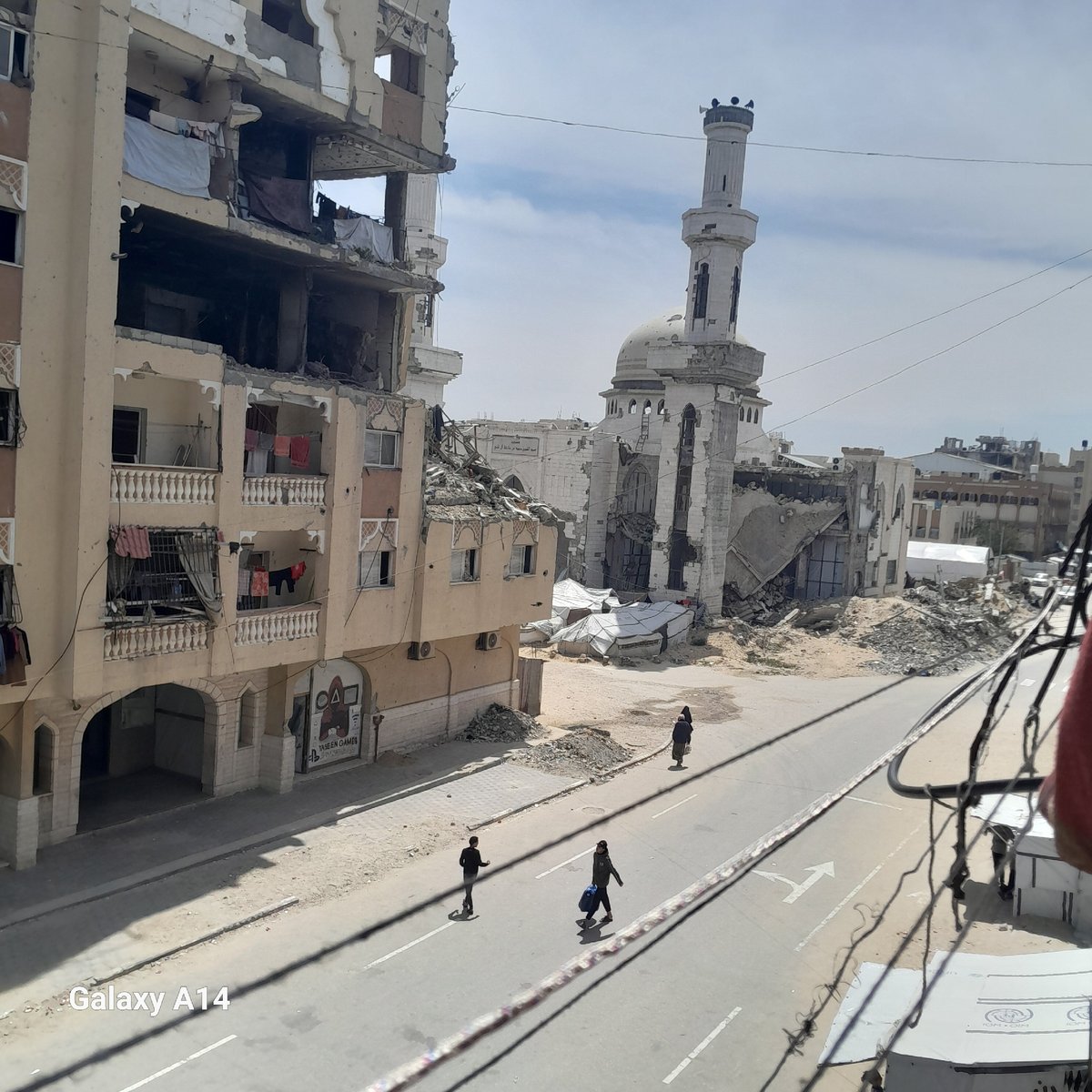 Urban street shows widespread building damage including mosque