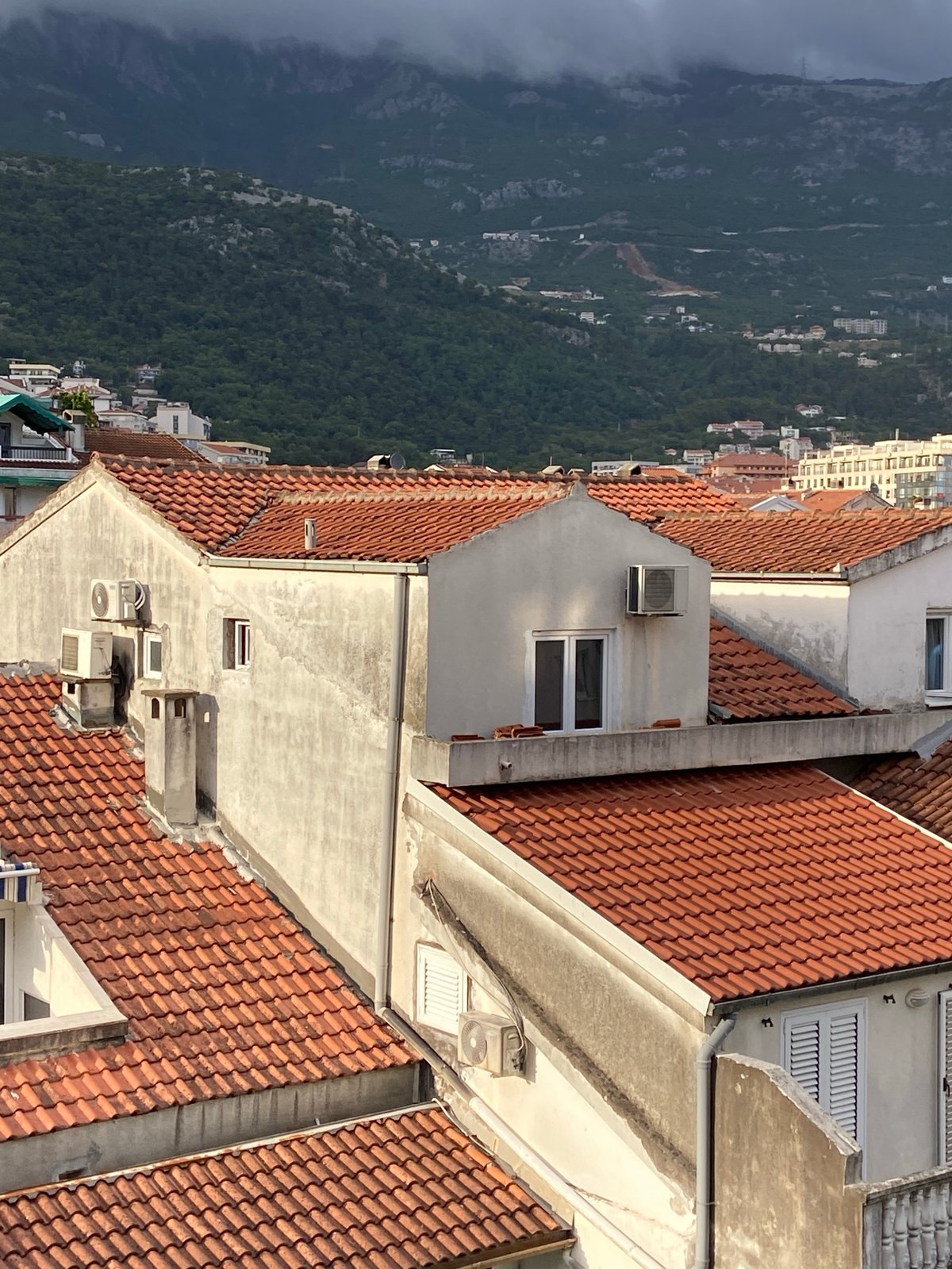 Aerial views document Budva's urban landscape under cloudy skies