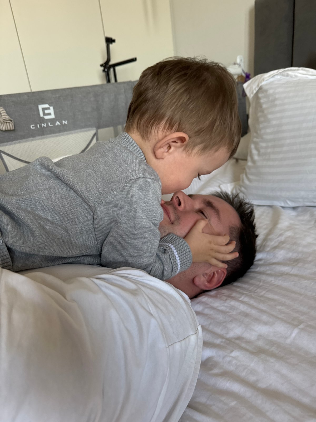 Father and toddler share quiet moment on bed in Odintsovo