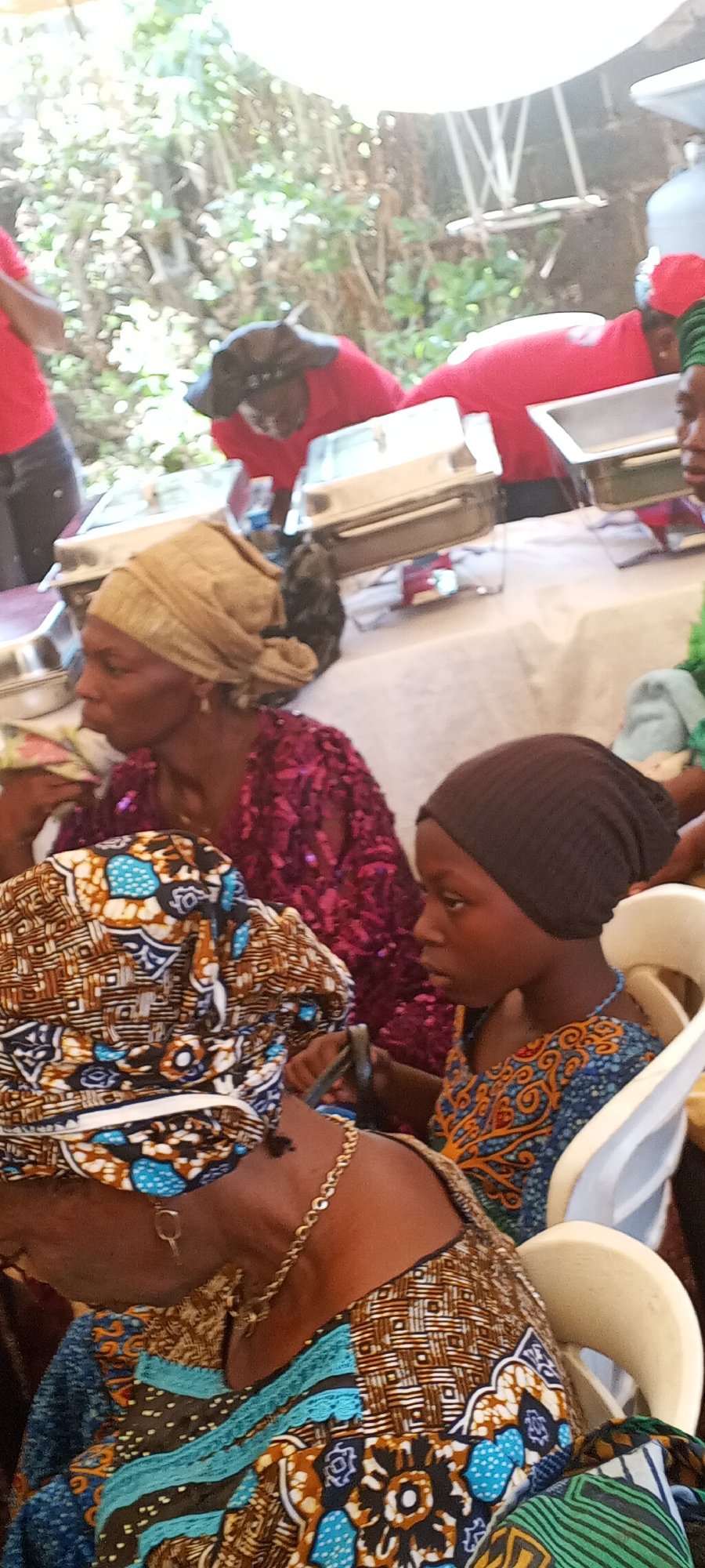 Community gathering features traditional dress under outdoor canopy