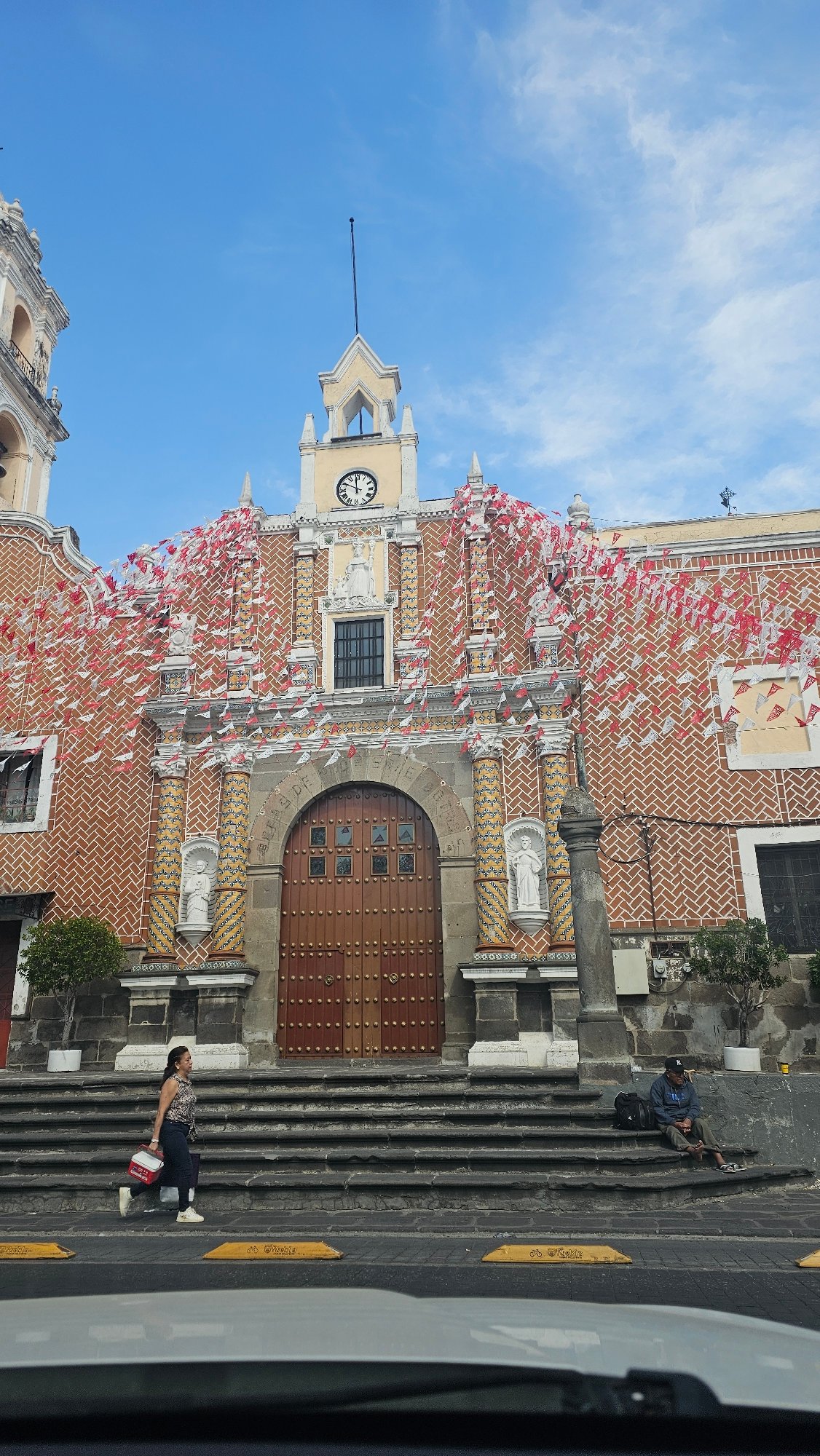 Historic Puebla church adorned with ceremonial red and white flags