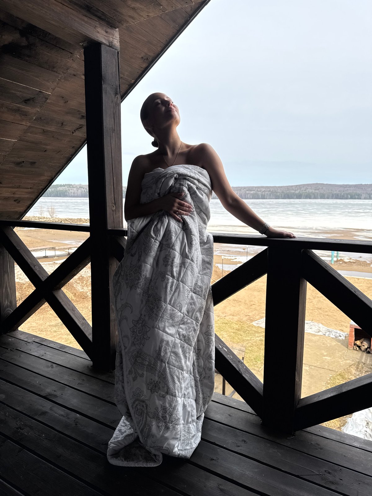 Woman in white blanket observed on balcony in Chaikovsky