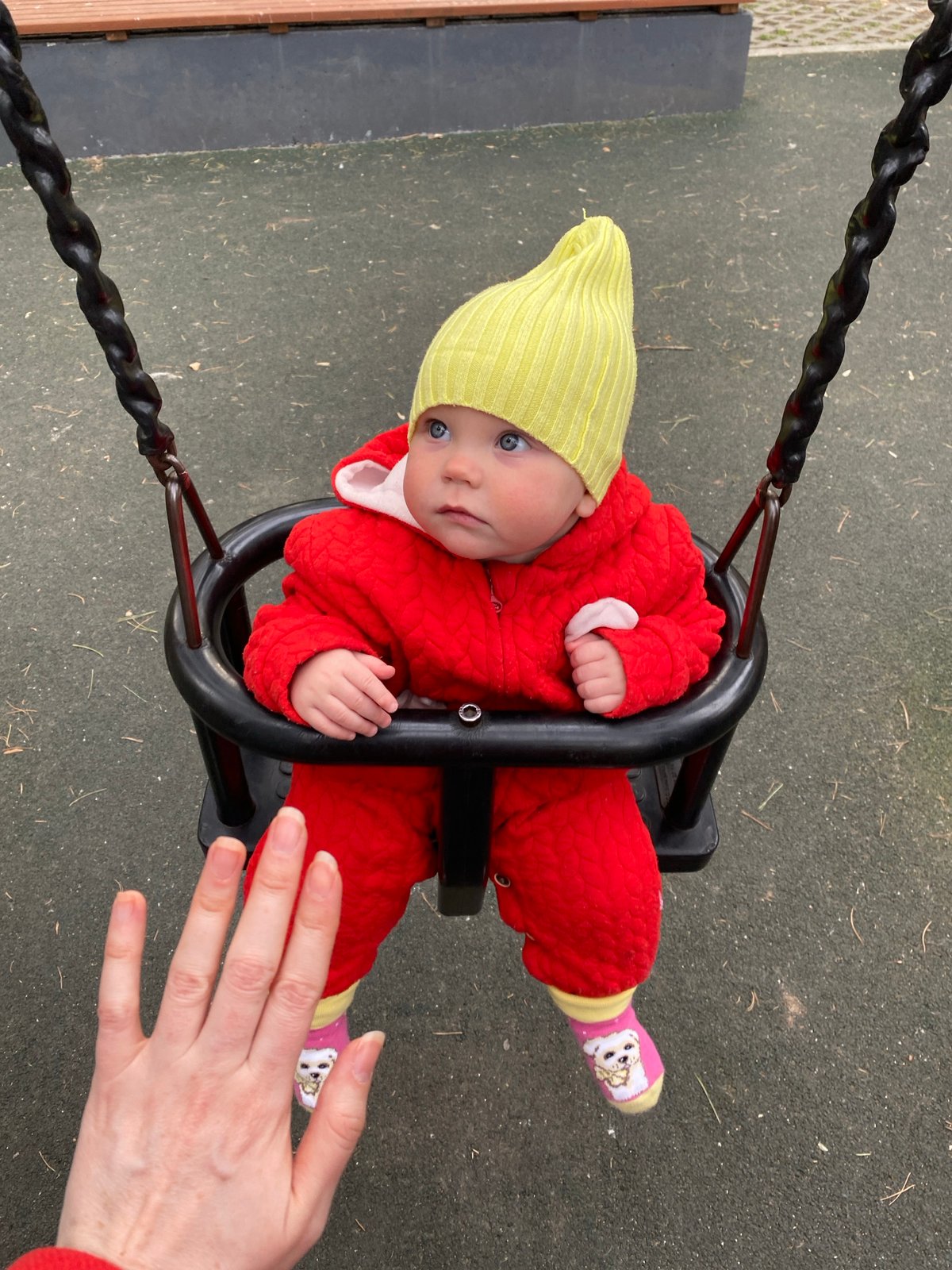 Baby plays in swing at Yekaterinburg playground during spring