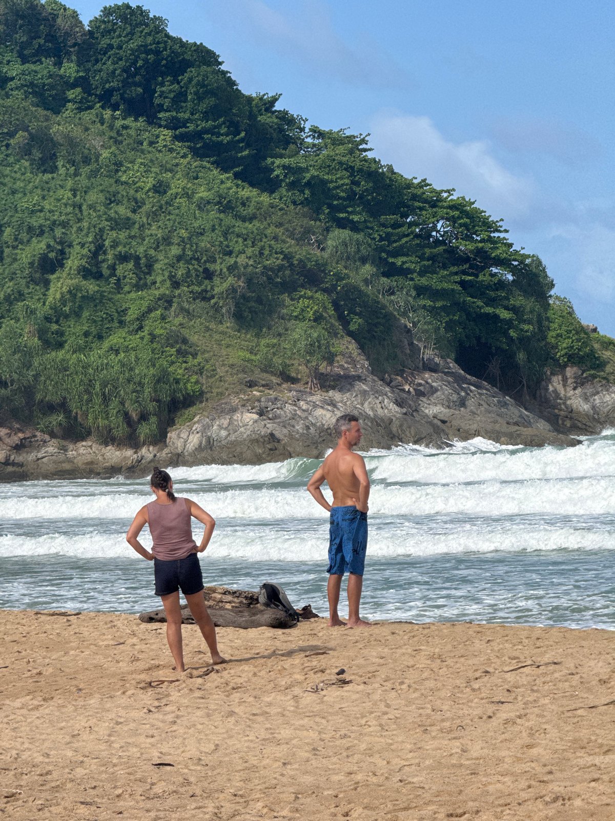 Kitesurfers and beachgoers at a flagged Rawai shoreline