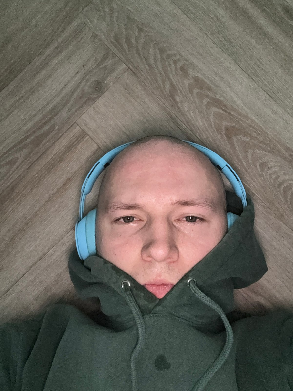 Person in headphones lies on wooden floor in Krasnoyarsk
