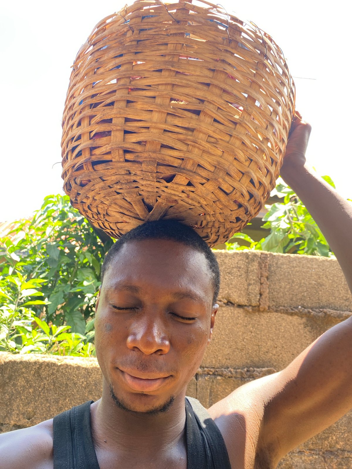 Carrying a large woven basket through Bukuru, Nigeria
