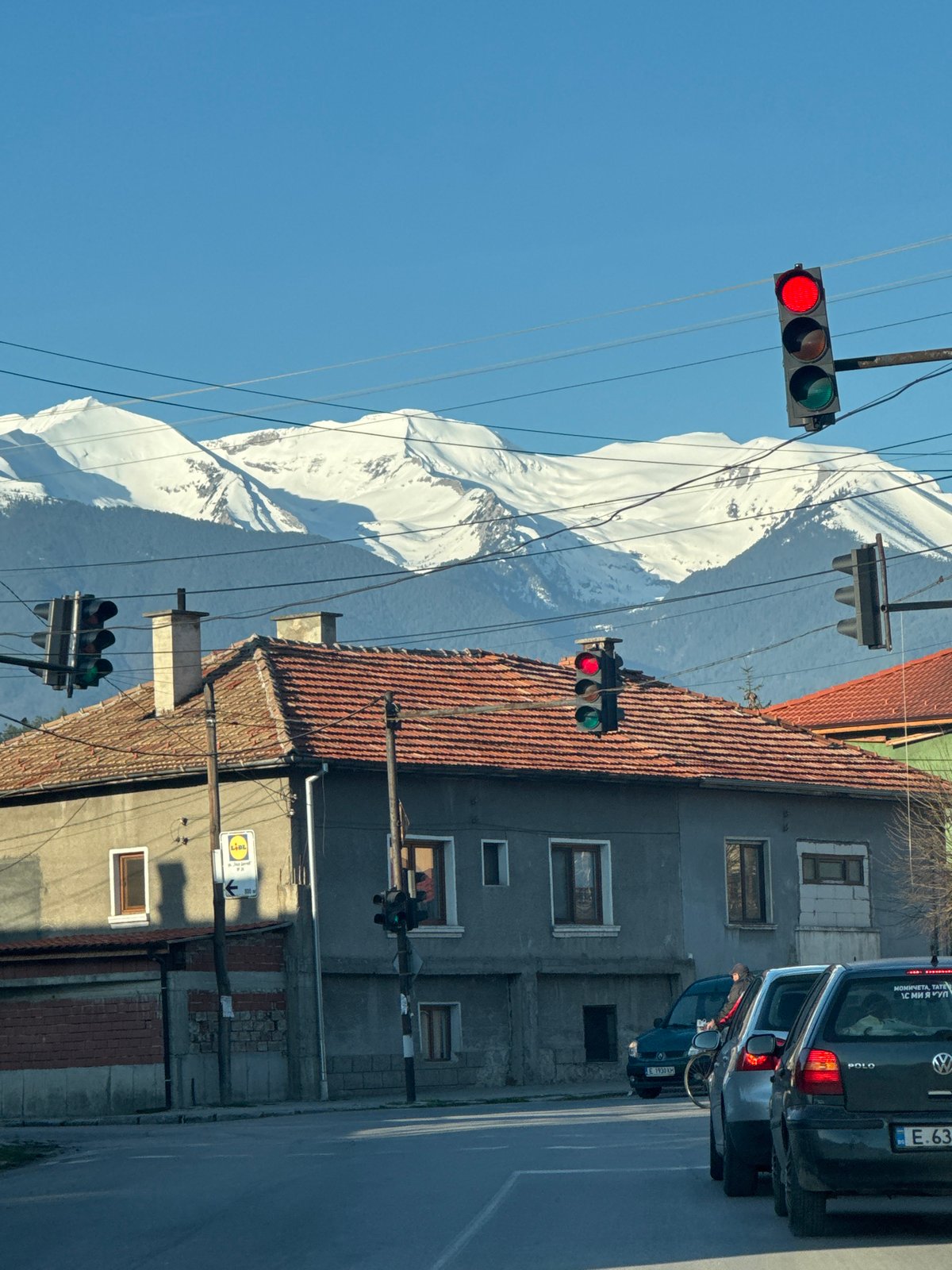 Morning street view captures snowy mountains behind Razlog traffic lights