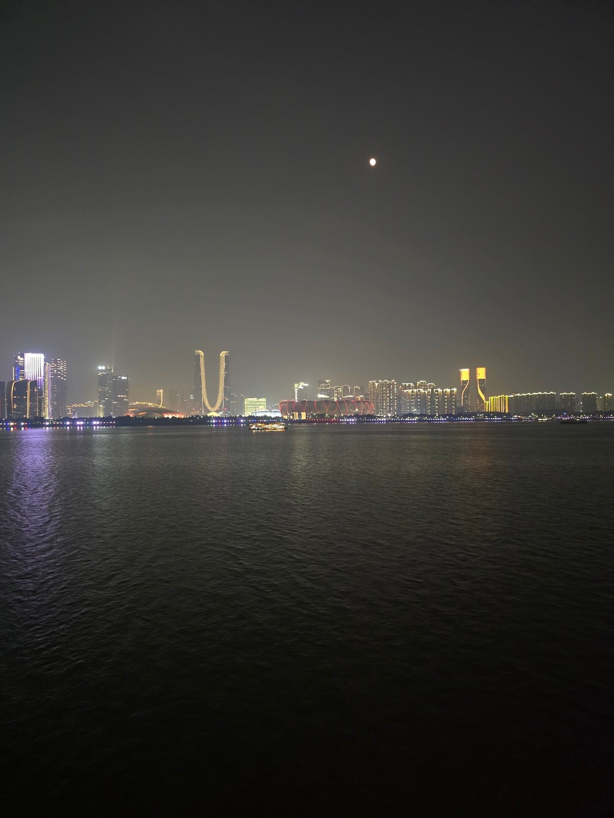 Shangcheng District skyline glowing across the water at night