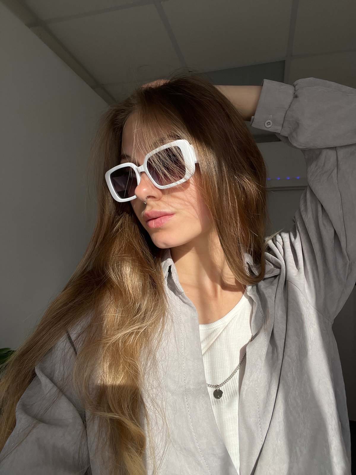 Woman takes selfies in sunlit room in Foki, Russia