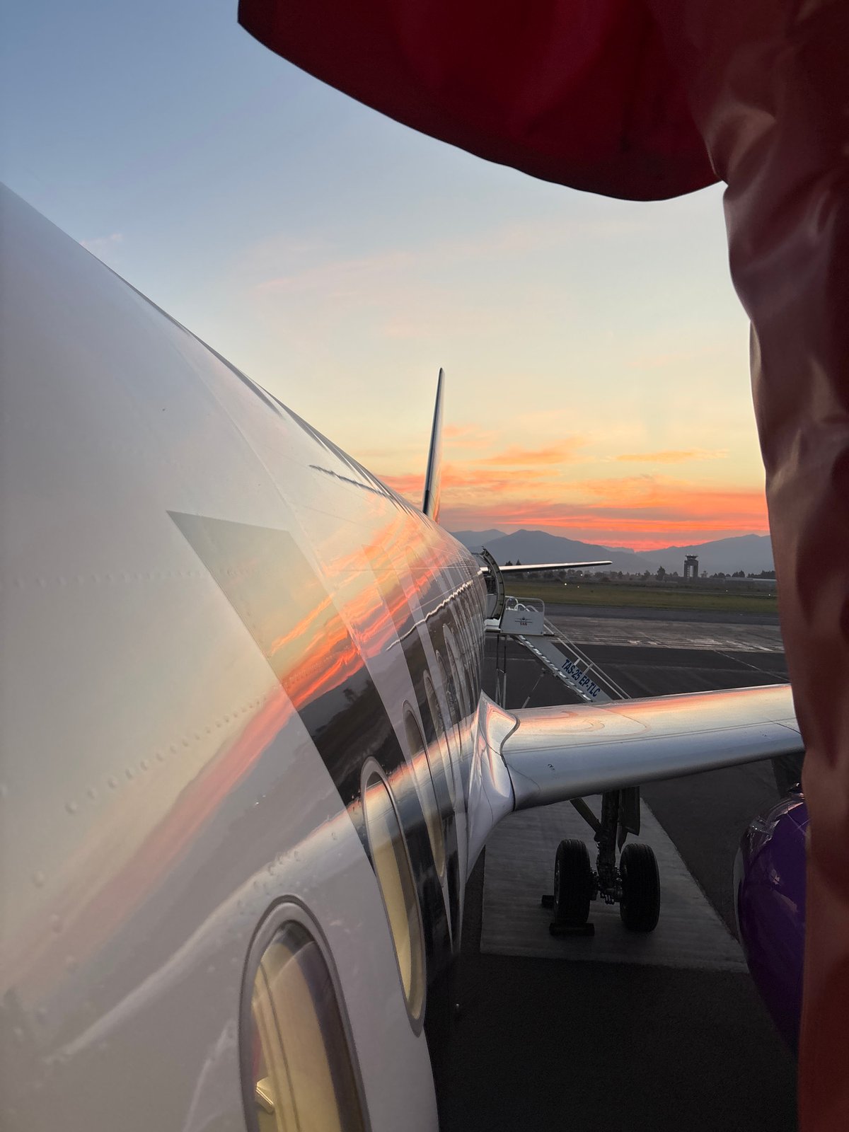 Volaris aircraft serviced on tarmac with boarding stairs attached