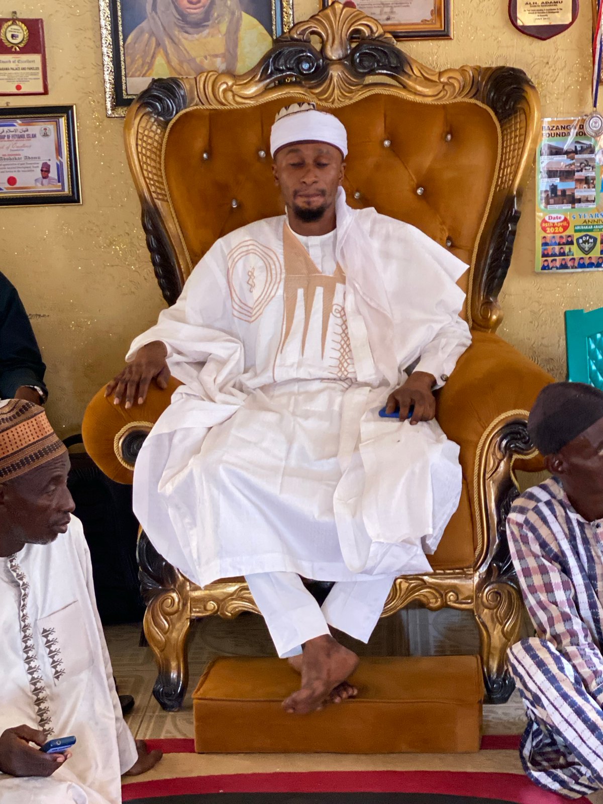 Man in traditional attire rests in ornate chair in Nigeria