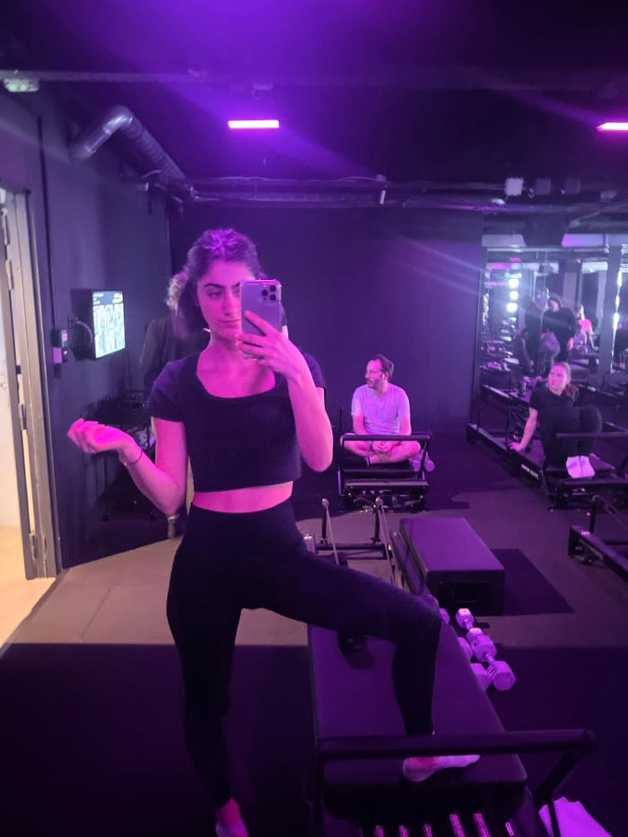 Woman takes selfie in purple-lit Paris fitness studio