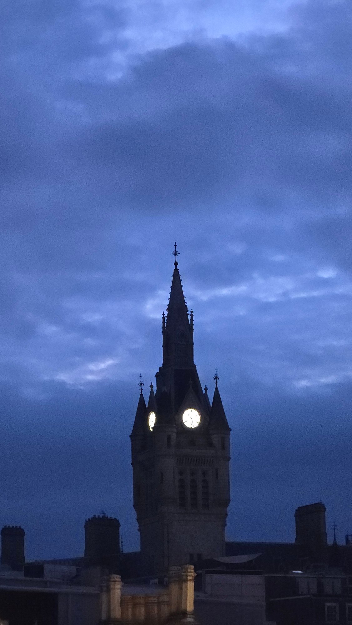 Gothic clock tower stands against Aberdeen's cloudy night sky