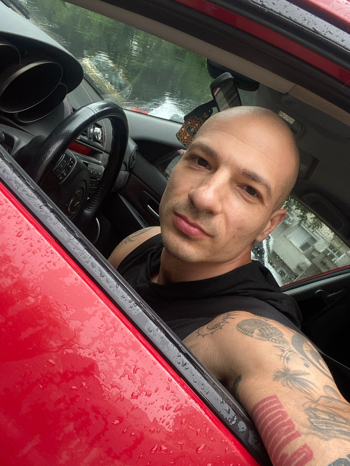 Man photographed twice in red car, outdoor selfie in Pleven