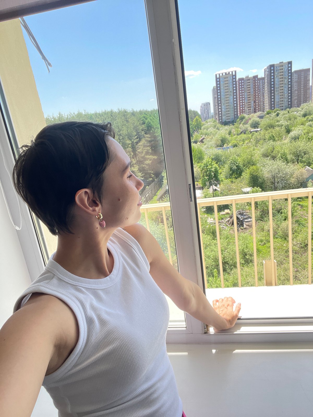 Woman opens window, gazes skyward in Izhevsk morning
