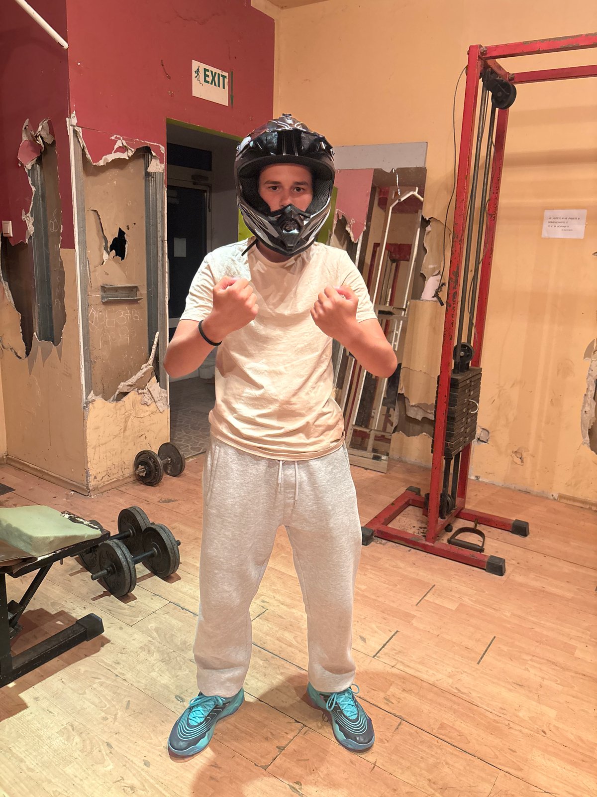 Helmeted person practices boxing in rundown Bulgarian gym