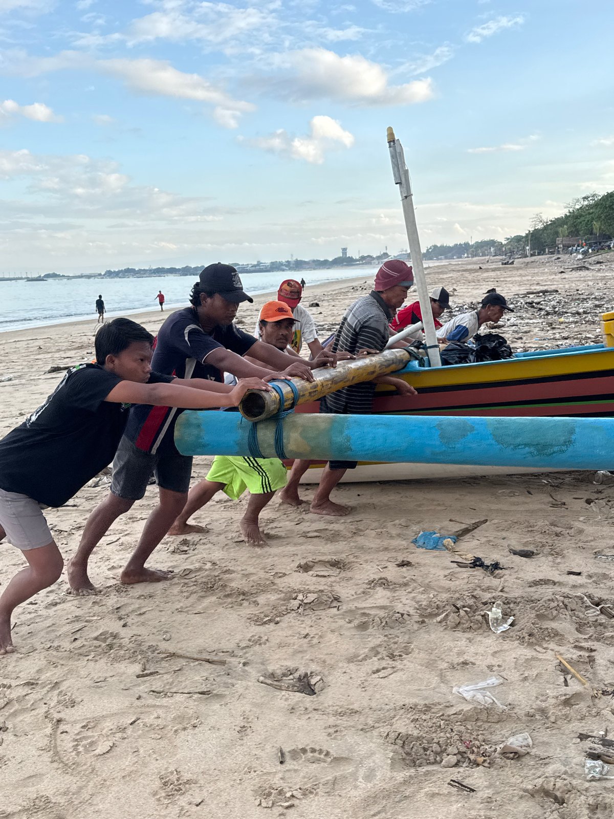 Men move traditional painted boat on Kuta beach