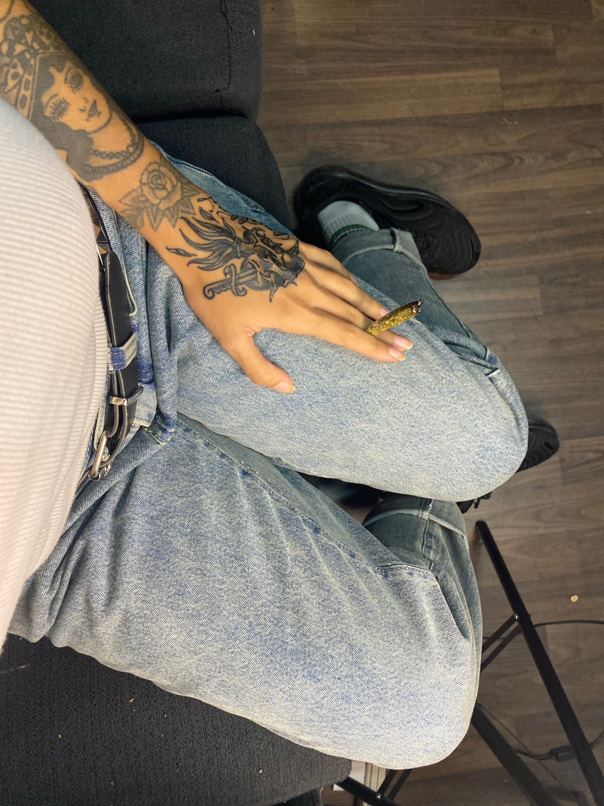 Person with tattoos sits on gray sofa in Llavallol