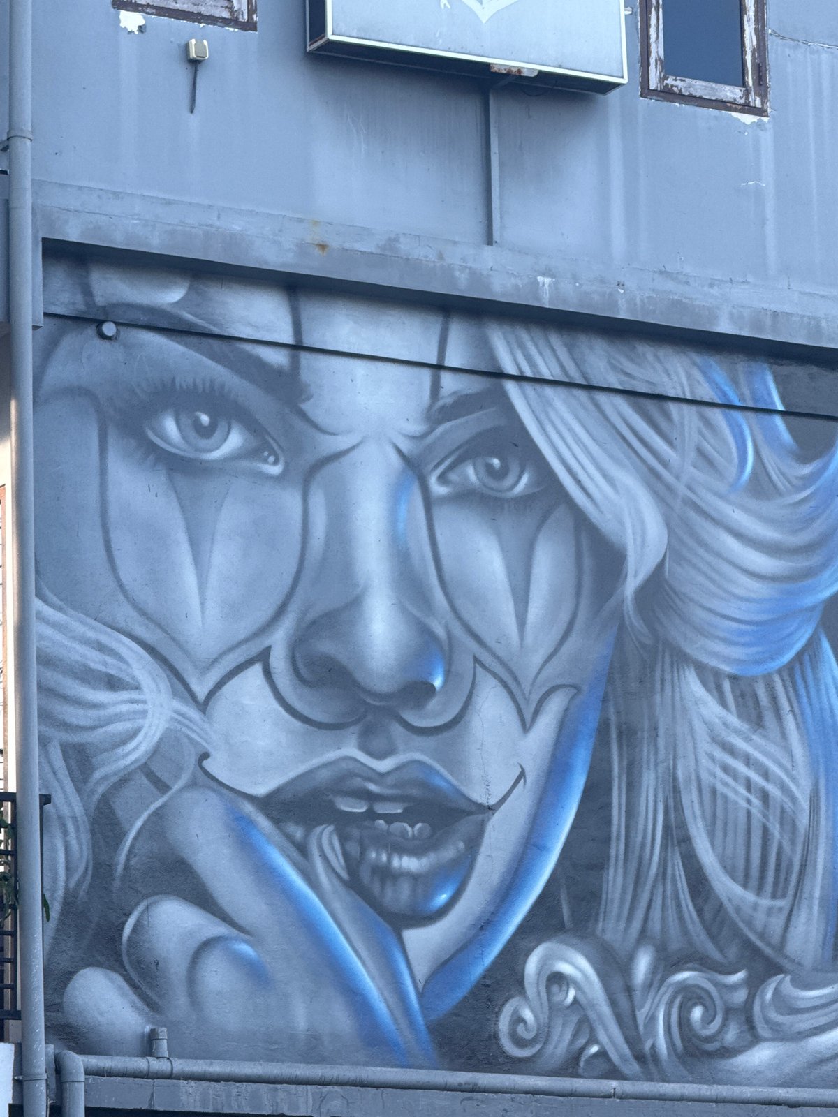 Blue and white face mural spotted on Kuta building