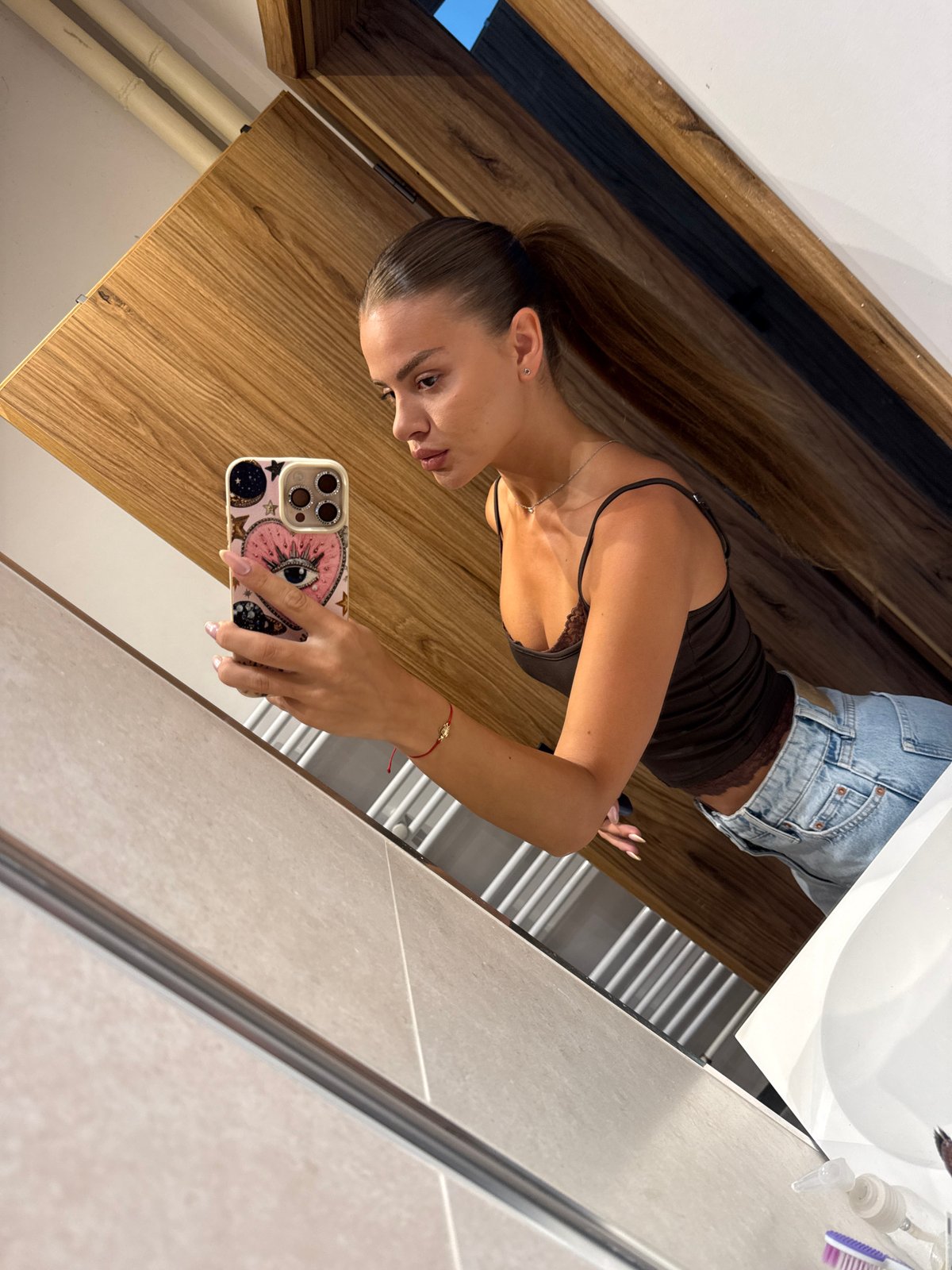Mirror selfie in a modern bathroom, dark top and denim