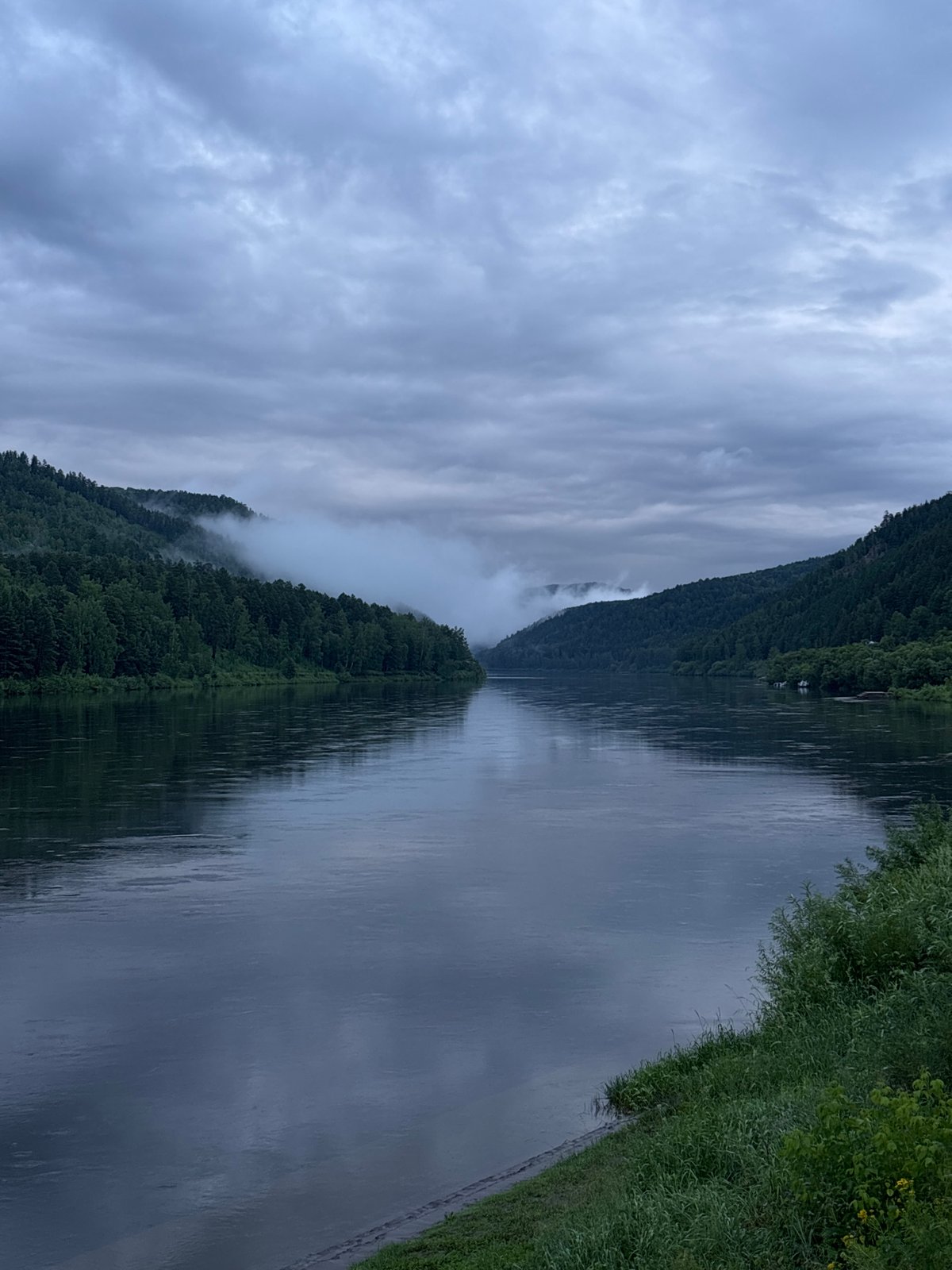 Misty river winds through forested hills in rural Siberia