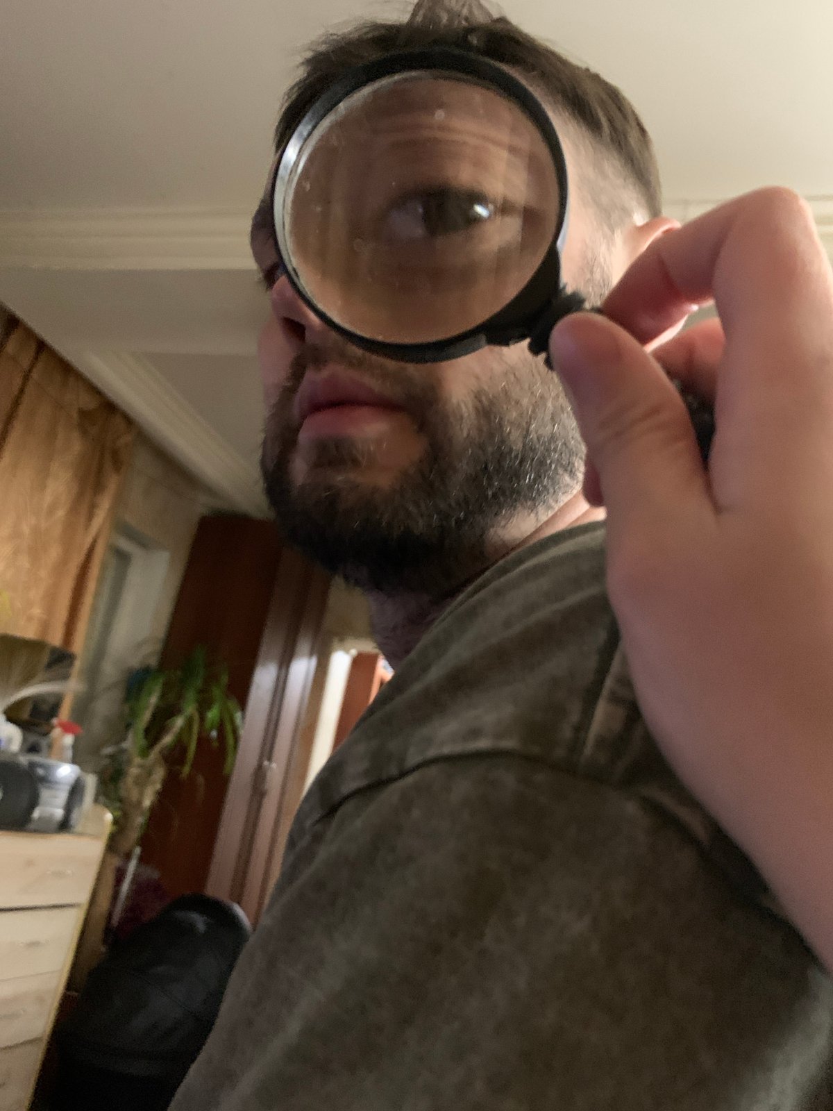 Man uses magnifying glass and mirror indoors in Zasechnyi