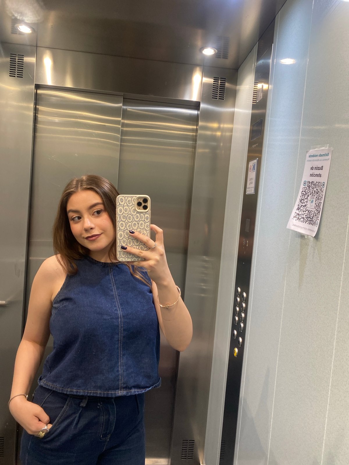 Woman Takes Selfie in Elevator While Wearing Denim Outfit