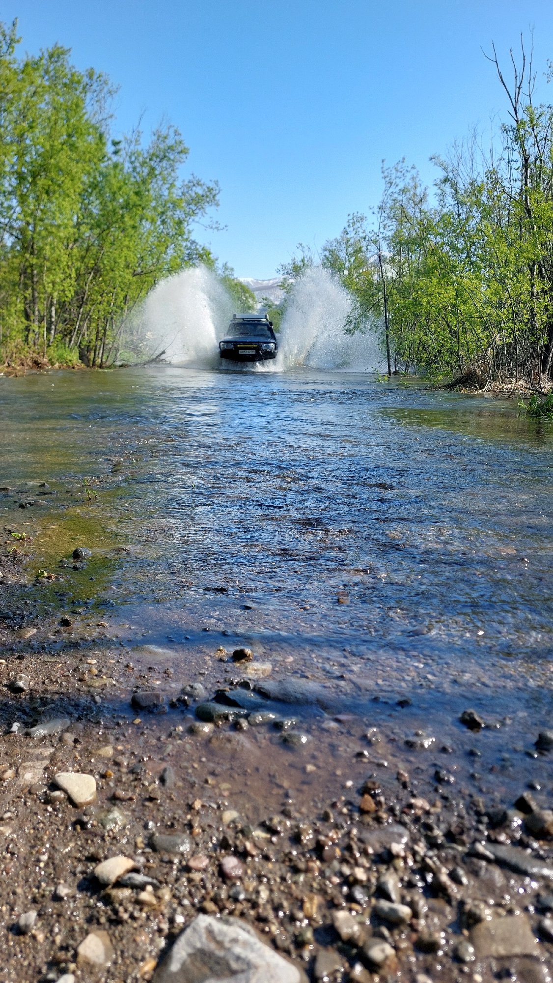 SUV crosses shallow river in remote Russian village