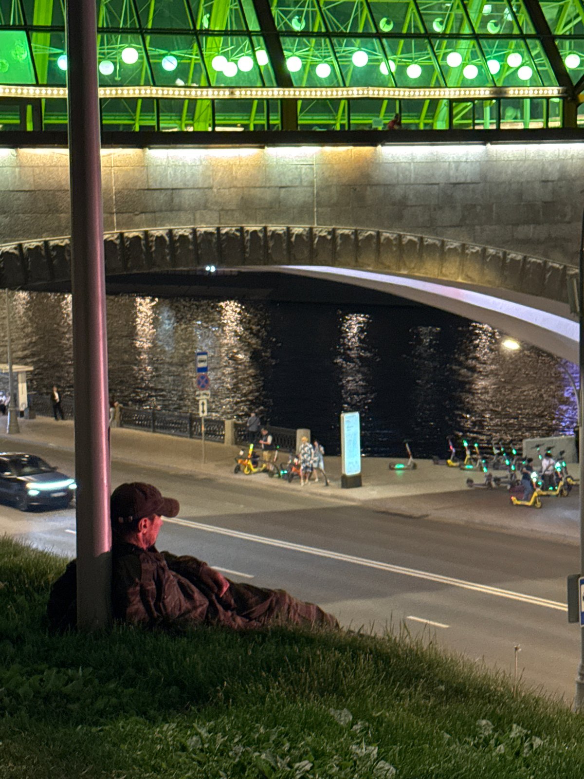 Man rests on Moscow riverbank embankment at night