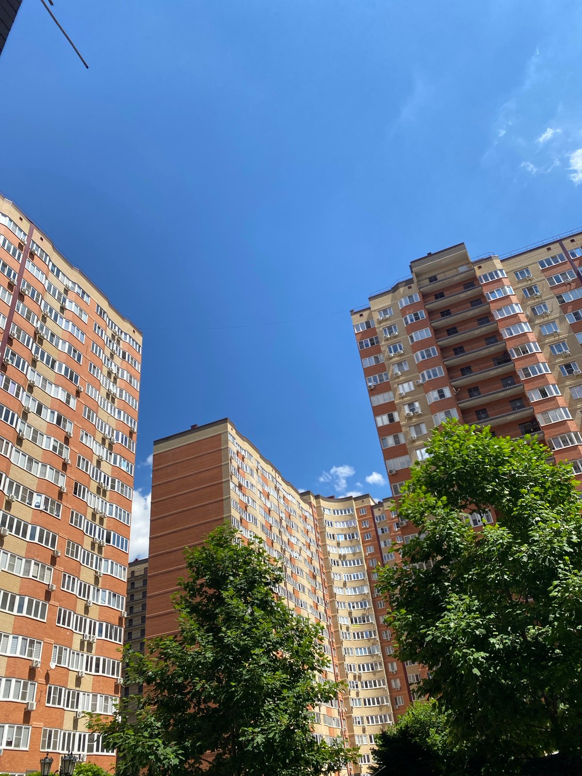 Tall modern apartment towers rise against a clear blue sky