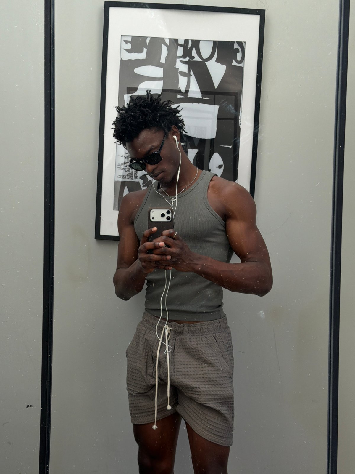 Man with smartphone and earbuds captured in London mirror reflection