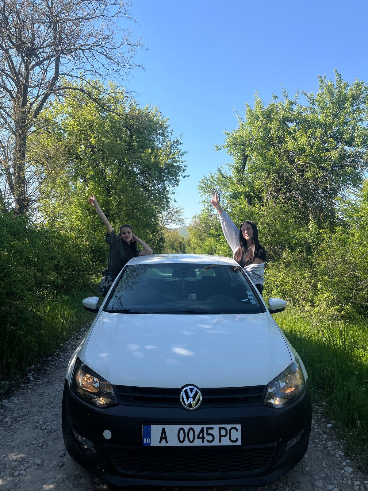 Two people pose with white Volkswagen in rural Bulgaria