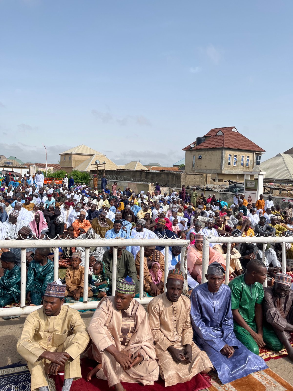 Large outdoor Muslim prayer gathering near gas station in Jos
